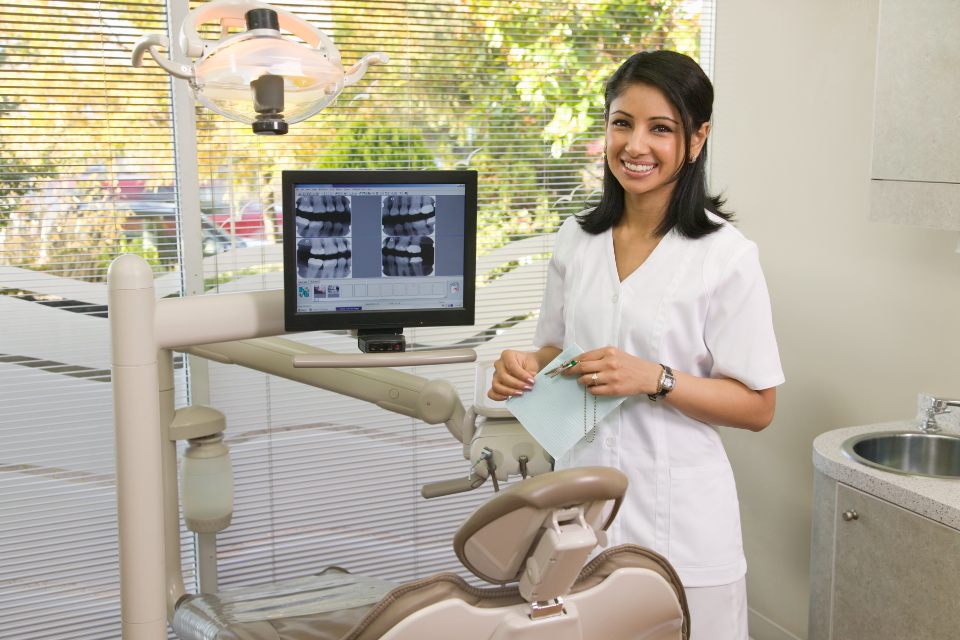 Female dentist wearing scrubs in dental room in front of teeth xray