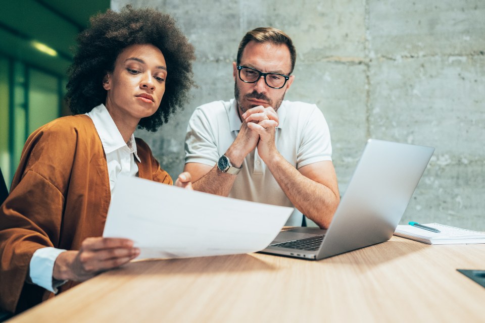 Professional woman and man sat in office room concentration on a piece of paper