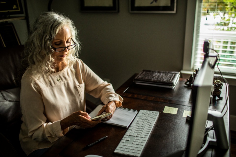 Professional woman in home office using phone