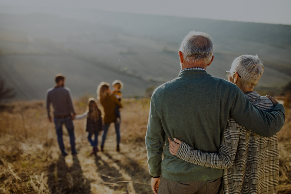 Retired couple look on at family walking together