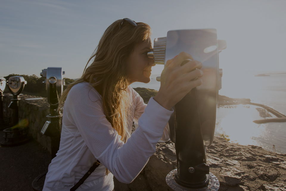 Woman looks out at view with a viewing scope