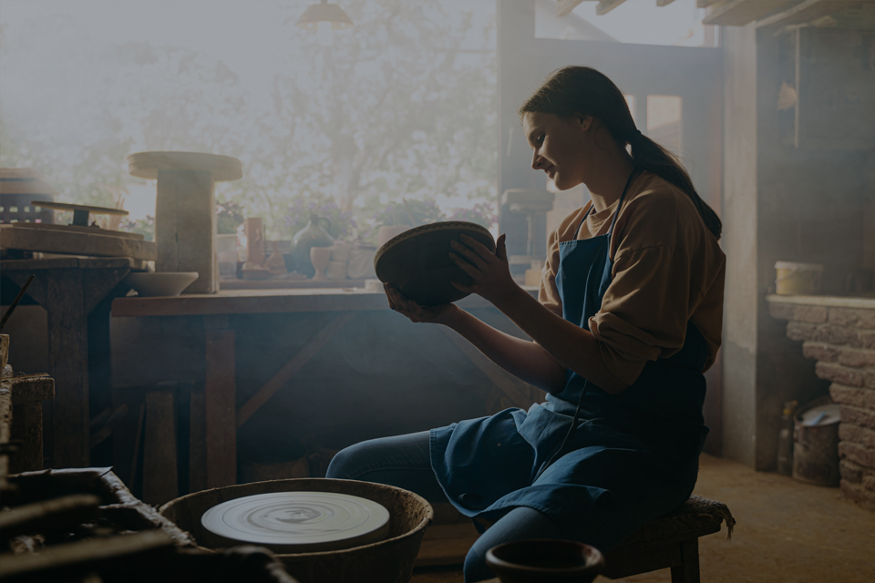 Young woman sat at pottery wheel