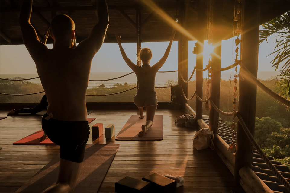 Yoga class performing yoga pose with sunrise