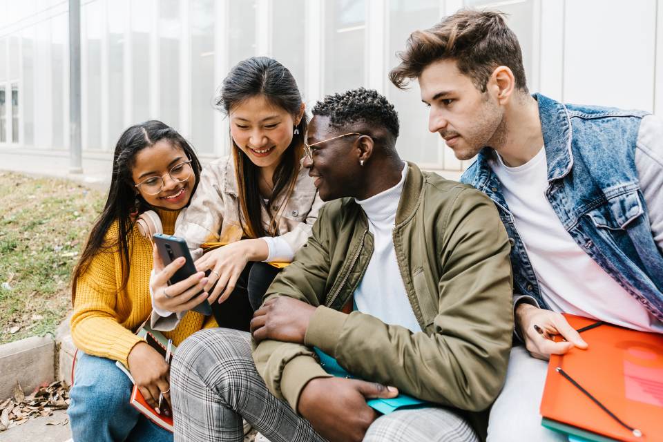 Students outside looking at phone