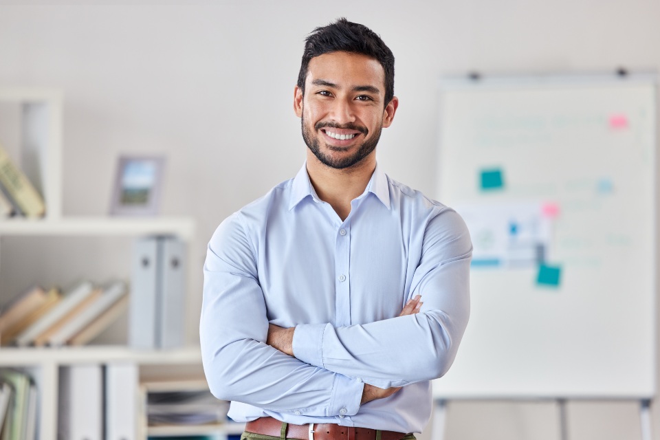 Professional male teacher in office smiling with crossed arms