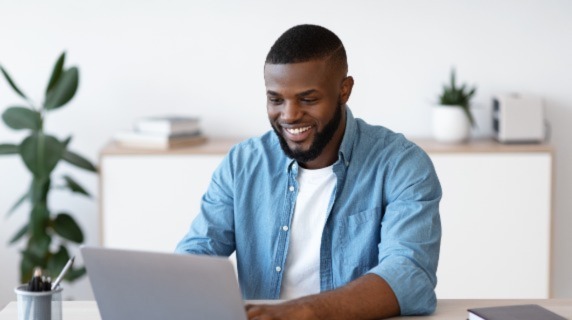 Young male professional at desk on laptop smiling