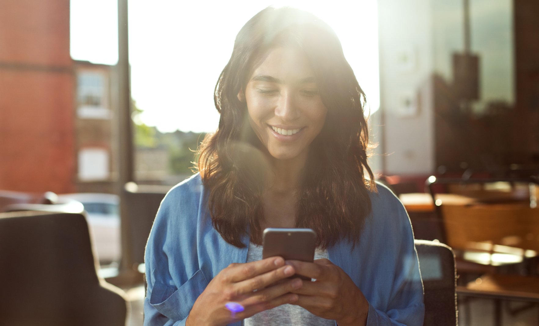 Woman looking at phone while smiling